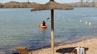 Playa en TAIGA Lake Caspe, parque vacacional en Aragón, España, con kayakista, tumbonas y sombrilla.