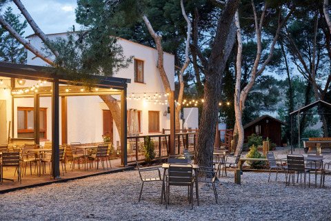 Outdoor seating with string lights at TAIGA Lake Caspe holiday park, surrounded by trees in Aragón, Spain.