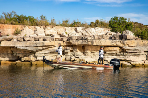 Dos personas pescando desde una lancha junto a las rocosas orillas de Caspe, Aragón, España.
