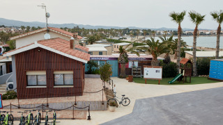 Vakantiepark met fietsen, minimarkt, speeltuin en palmbomen bij zee in TAIGA Delta de l'Ebre, Catalonië.