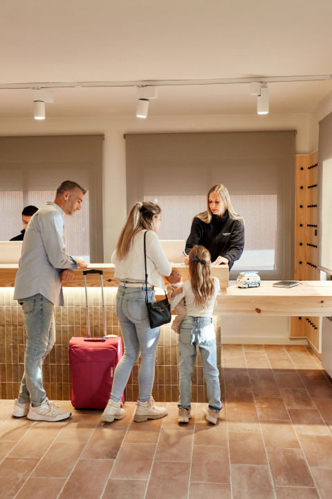 Gezin aan het inchecken bij de receptie van TAIGA Delta de l'Ebre vakantiepark in Catalonië, Spanje.