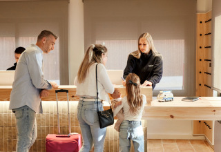 Gezin checkt in bij de receptie van TAIGA Delta de l'Ebre vakantiepark in Catalonië, Spanje.