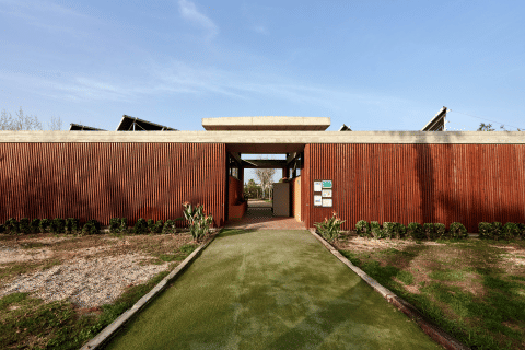 Ingang van vakantiepark TAIGA Delta de l'Ebre in Catalonië, Spanje, met houten gevel en groen pad.