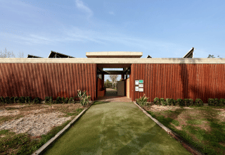 Entrée du parc de vacances TAIGA Delta de l'Ebre en Catalogne, Espagne, avec façade en bois et allée verte.