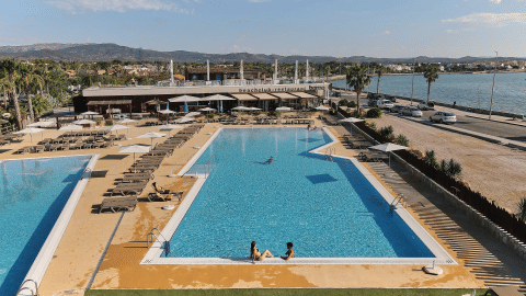Piscine extérieure et chaises longues au parc de vacances TAIGA Delta de l'Ebre en Catalogne, Espagne, près de l'eau.