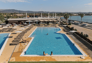 Piscina all'aperto e lettini al villaggio vacanze TAIGA Delta de l'Ebre in Catalogna, Spagna, vicino all'acqua.