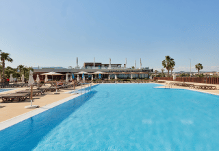 Außenpool mit Liegestühlen und Sonnenschirmen im TAIGA Delta de l’Ebre Ferienpark in Katalonien, Spanien.
