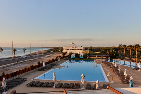Zicht op het zwembad van het TAIGA Delta de l'Ebre vakantiepark in Catalonië, Spanje, met de zee op de achtergrond.