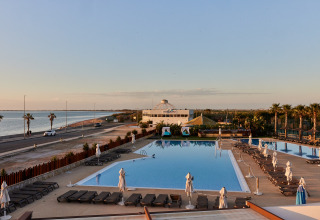 Zicht op het zwembad van het TAIGA Delta de l'Ebre vakantiepark in Catalonië, Spanje, met de zee op de achtergrond.