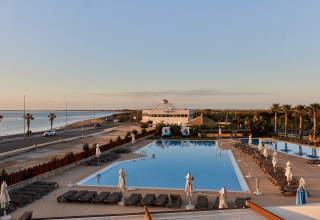 Vista de la zona de la piscina en el parque vacacional TAIGA Delta de l'Ebre en Cataluña, España, con el mar de fondo.