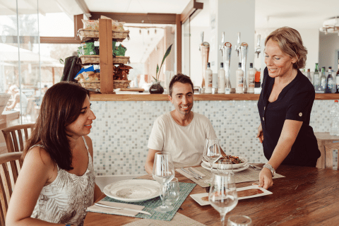 A couple enjoys dining while a waitress serves food at TAIGA Delta de l'Ebre holiday park in Catalonia, Spain.