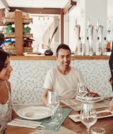 Zwei Gäste werden von einer freundlichen Kellnerin im Restaurant der TAIGA Delta de l'Ebre Ferienanlage bedient.