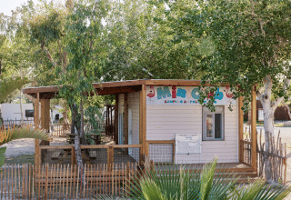 Cabane en bois 'Mini Club' entourée d'arbres au parc de vacances TAIGA Delta de l'Ebre en Catalogne, Espagne.