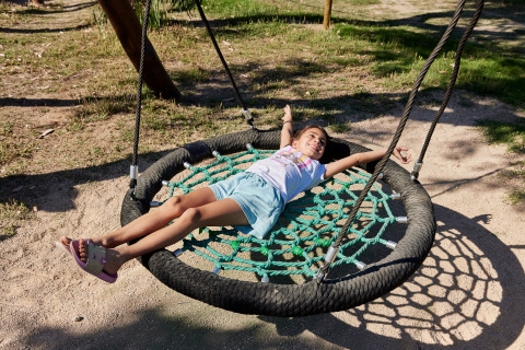 A child relaxes on a rope swing in the sun at TAIGA Delta de l'Ebre holiday park in Catalonia, Spain.