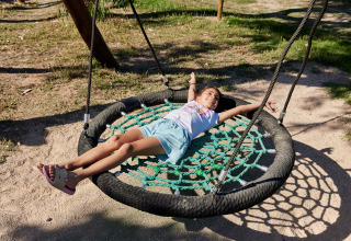 Et barn slapper af på en gynge i solen på TAIGA Delta de l'Ebre feriepark i Catalonien, Spanien.