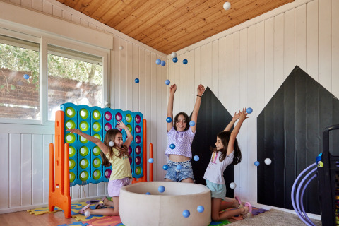Tres niños juegan y lanzan pelotas en una sala de juegos en TAIGA Delta de l'Ebre, parque vacacional de Cataluña.