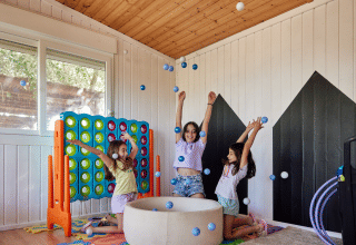Trois enfants jouent en lançant des balles dans une salle de jeux à TAIGA Delta de l'Ebre, parc de vacances en Catalogne.