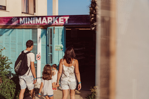 Een gezin stapt een minimarkt binnen aan het TAIGA Delta de l'Ebre vakantiepark in Catalonië, Spanje.