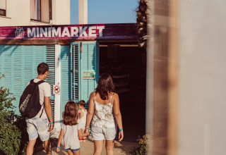 Een gezin stapt een minimarkt binnen aan het TAIGA Delta de l'Ebre vakantiepark in Catalonië, Spanje.