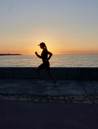 Una persona corriendo junto al mar al atardecer cerca de L'Ampolla, Cataluña, España.