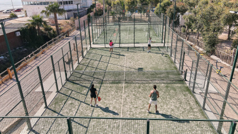 Parque vacacional en Cataluña, España, con pistas de pádel y huéspedes disfrutando un juego deportivo.