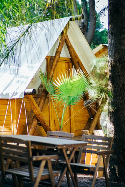 Vista exterior de la cabaña Janda Tent en TAIGA Tarifa, España, con muebles de madera y plantas verdes