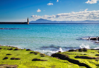 Kystlandskab nær Tarifa, Cádiz, Spanien med klart blåt hav, grønne klipper og udsigt til bjergene.