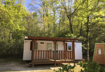 Cabaña Bungalow Larraun rodeada de árboles verdes y naturaleza, con un porche de madera bajo cielo azul.