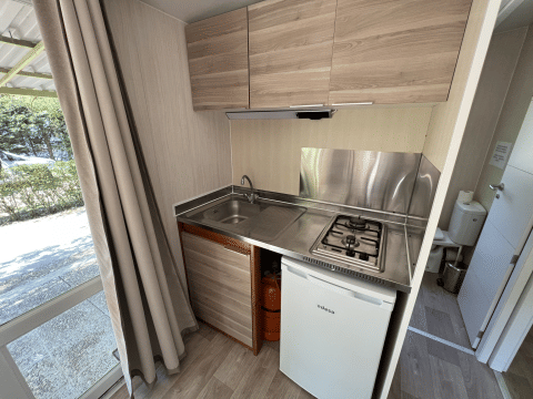 Modern kitchenette in Bungalow Urbasa at Camping Etxarri, Spain, featuring gas stove and mini fridge.