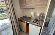 Modern kitchenette in Bungalow Urbasa at Camping Etxarri, Spain, featuring gas stove and mini fridge.