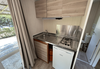 Modern kitchenette in Bungalow Urbasa at Camping Etxarri, Spain, featuring gas stove and mini fridge.