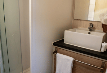 Baño compacto en Bungalow Urbasa de Camping Etxarri, España, con lavabo cuadrado, espejo y ducha.