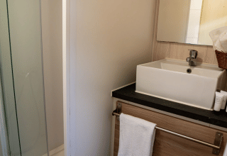 Baño compacto en Bungalow Urbasa de Camping Etxarri, España, con lavabo cuadrado, espejo y ducha.