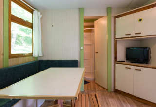Interior del Bungalow Aratz en Camping Etxarri, España, con mesa, sofá esquinero, TV y baño.