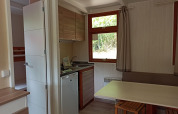 Interno del Bungalow Aratz al Camping Etxarri in Spagna con angolo cottura, tavolo e finestra sul verde.