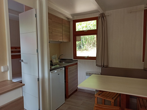 Interiør af Bungalow Aratz på Camping Etxarri i Spanien med køkken, spisebord og vindue til naturen.