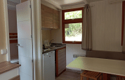 Interior del Bungalow Aratz en Camping Etxarri, España, con cocina, mesa de comedor y ventana al exterior.