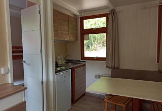 Interiør af Bungalow Aratz på Camping Etxarri i Spanien med køkken, spisebord og vindue til naturen.