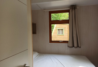 Interior view of Bungalow Aratz at Camping Etxarri in Spain, showing a bed and window facing another cabin.