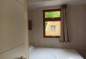 Vista interna del Bungalow Aratz al Camping Etxarri in Spagna con letto e finestra che mostra un'altra cabina.