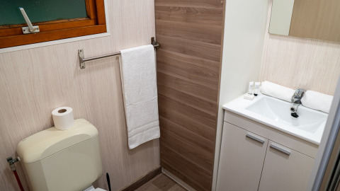 Badeværelse i Bungalow Aratz med toilet, vask, spejl og håndklæde på Camping Etxarri i Spanien.