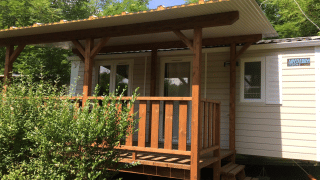 Photo of Mobile home Urederra, a cozy cabin with a wooden porch and lush greenery around it.