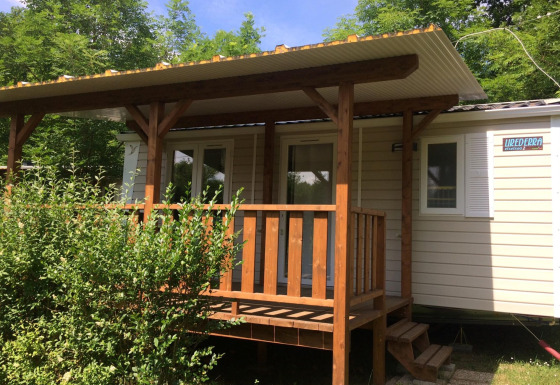 Afbeelding van Mobile home Urederra, een knusse blokhut met houten veranda en veel groen rondom.