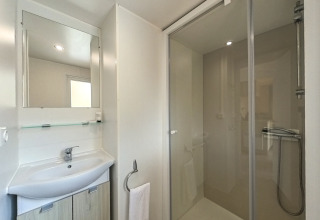 Badkamer in Mobile home Urederra met douche, wastafel, spiegel en handdoek op Camping Etxarri, Spanje.