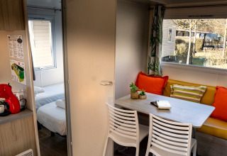 Interieur van Mobile home Urederra op Camping Etxarri in Spanje, met eetgedeelte en kleurrijke kussens.
