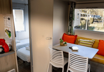 Interno della casa mobile Urederra al Camping Etxarri in Spagna, con zona pranzo e cuscini colorati.