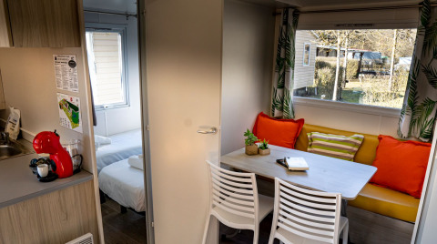 Interno della casa mobile Urederra al Camping Etxarri in Spagna, con zona pranzo e cuscini colorati.
