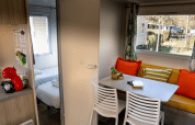 Intérieur du Mobil-home Urederra au Camping Etxarri en Espagne, avec coin repas et coussins colorés.