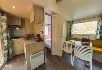Interno della Mobile home Urederra al Camping Etxarri in Spagna, con cucina, zona pranzo e ampie finestre.
