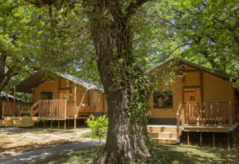 Tende safari a Glamping Haritza con veranda in legno, immerse in una lussureggiante foresta verde.